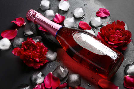 Bottle of cold champagne and flowers on dark backgroundの写真素材
