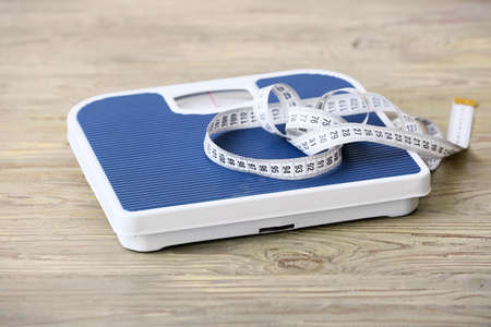 Floor scales and measuring tape on wooden background. Concept of anorexiaの写真素材