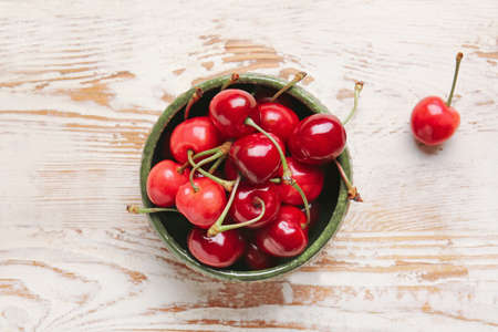 Bowl with sweet cherry on table