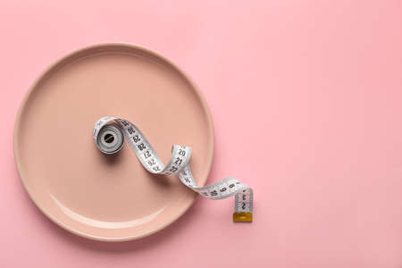Plate with measuring tape on color background. Concept of anorexiaの写真素材