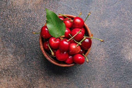 Bowl with sweet cherry on table