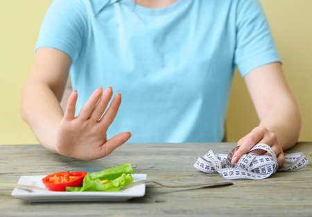 Skinny woman refusing to eat vegetables at table. Concept of anorexia