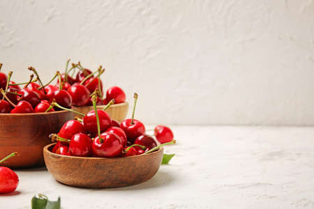 Bowls with sweet cherry on light backgroundの写真素材