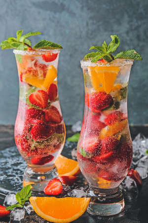 Glasses of fresh strawberry mojito on dark background