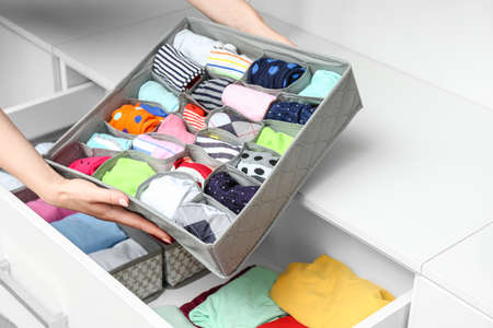 Woman with clean clothes in organizer at homeの写真素材