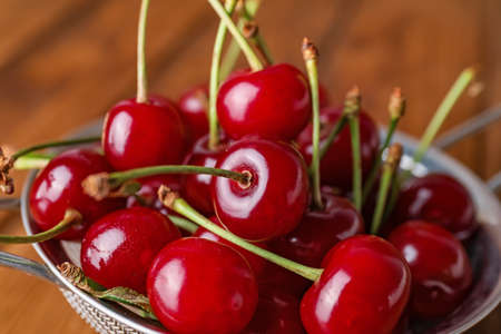 Sieve with sweet cherry on table, closeup
