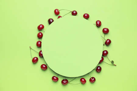 Ripe sweet cherry and blank card on color backgroundの写真素材