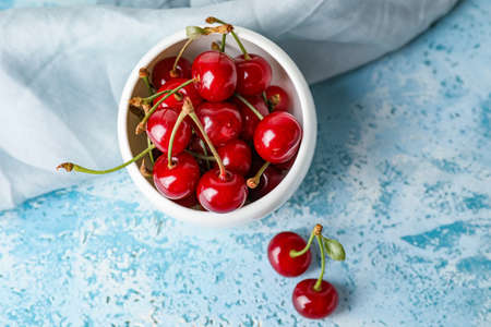 Bowl with sweet cherry on table