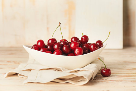 Bowl with sweet cherry on tableの写真素材