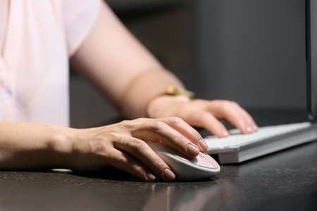 Woman using PC mouse while working on computer at table, closeup