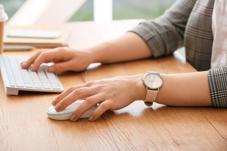 Woman using PC mouse while working on computer at table, closeupの写真素材