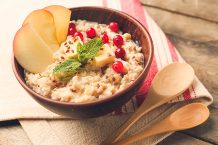 Bowl with tasty sweet oatmeal on tableの写真素材
