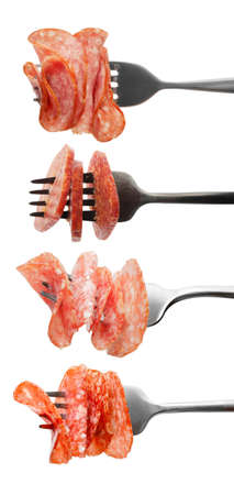 Forks with impaled slices of tasty smoked sausages on white background