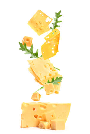 Tasty cheese with flying pieces and arugula on white backgroundの写真素材