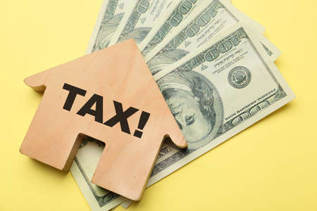 Model of house and dollar banknotes on color background. Concept of taxesの写真素材