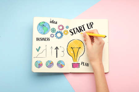 Woman writing business plan in notebook on color background