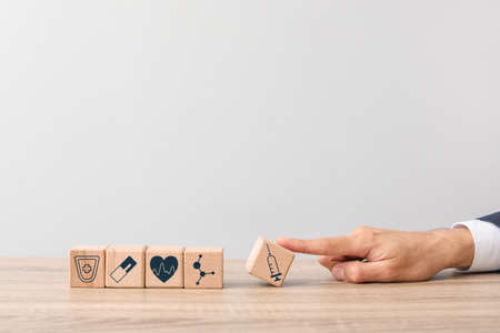 Wooden cubes and male hand on table. Health care insurance conceptの写真素材
