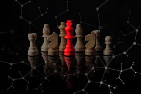 Red chess piece among ordinary ones on dark background