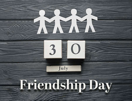Paper human figures and calendar with date of Friendship day on wooden backgroundの写真素材