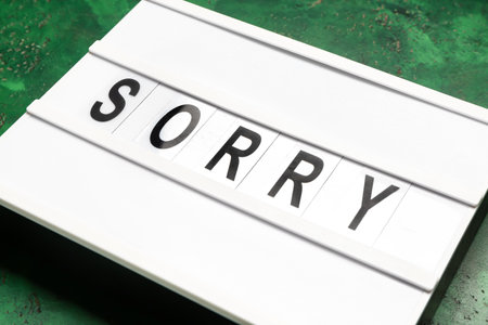 Board with word SORRY on color background