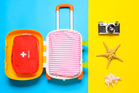 Suitcase with travel accessories for children on color backgroundの写真素材