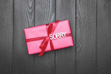 Gift with word SORRY on dark background