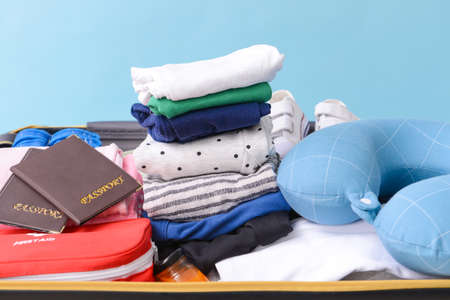 Suitcase with travel accessories for children on color background