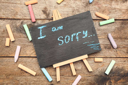 Chalkboard with text I AM SORRY on wooden backgroundの写真素材