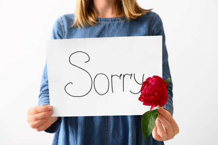 Woman holding paper with word SORRY on white background, closeupの写真素材
