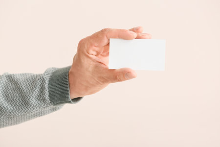 Male hand with blank business card on light backgroundの写真素材