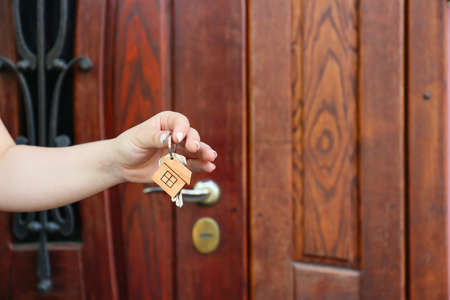 Woman with keys from house near door outdoors