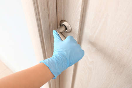 Woman wearing medical glove to open door
