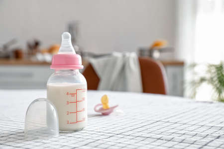 Bottle of milk for baby and pacifier on table