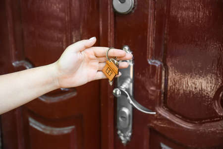 Woman with keys from house near door outdoorsの写真素材