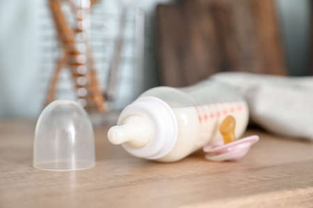 Bottle of milk for baby and pacifier on table