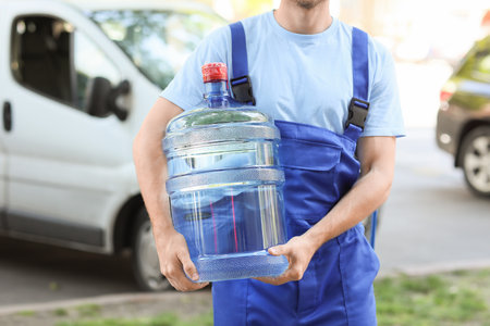 Delivery man with bottle of water outdoorsの写真素材