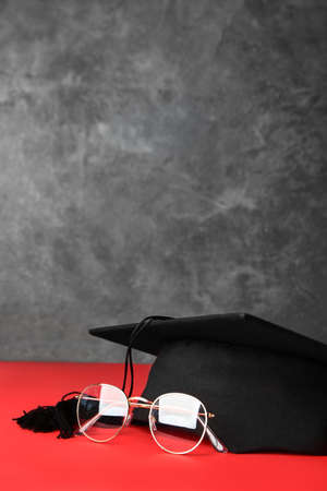 Graduation hat, glasses and diploma on tableの写真素材