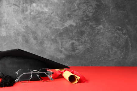 Graduation hat, glasses and diploma on tableの写真素材