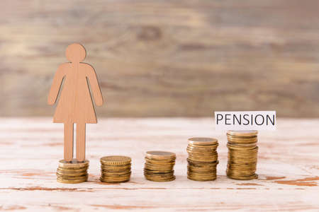 Female figure with coins and word PENSION on tableの写真素材