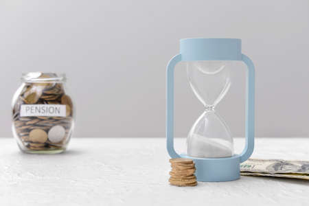 Hourglass with money on table. Concept of pensionの写真素材
