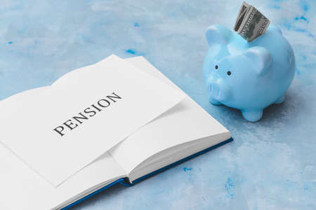 Piggy bank with book and word PENSION on color backgroundの写真素材