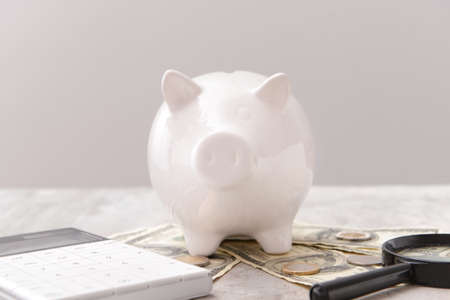 Piggy bank with money, calculator and magnifier on gray background. Concept of pensionの写真素材