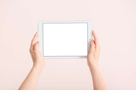 Hands with modern tablet computer on light background