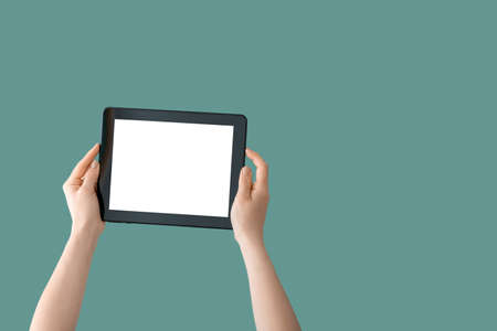 Hands with modern tablet computer on color backgroundの写真素材