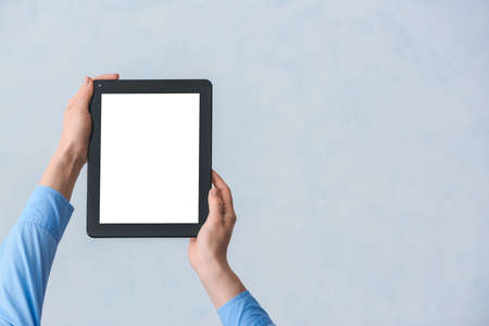 Hands with modern tablet computer on gray background