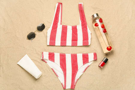 Stylish beach accessories on sand background