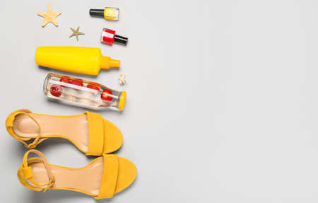 Female shoes with nail polishes, sunscreen and bottle of water on light backgroundの写真素材