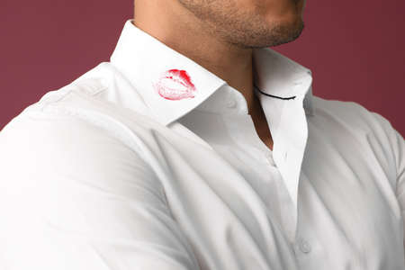 Young businessman with lips print on shirt collar against color background, closeupの写真素材