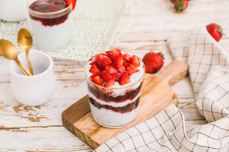 Tasty strawberry dessert in glass on table