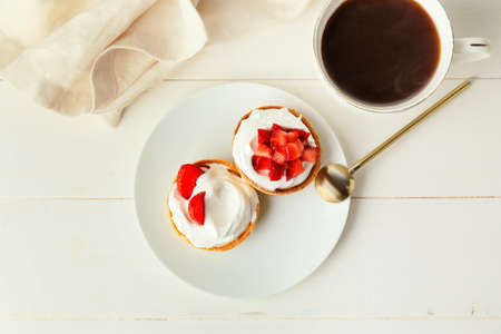 Plate with tasty tartlets and cup of coffee on table